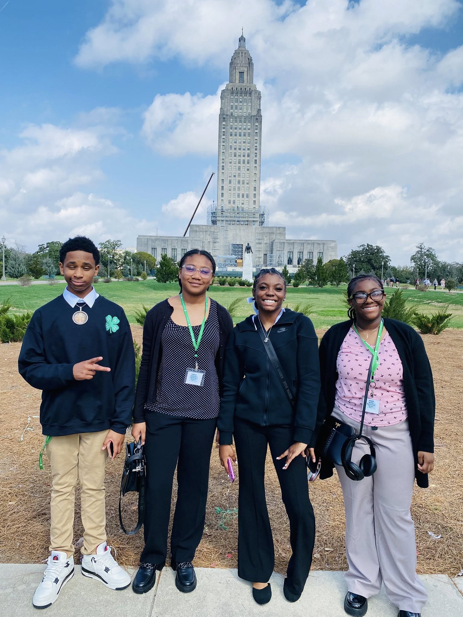 A boy and three girls posing in front of the Louisiana State Capitol.